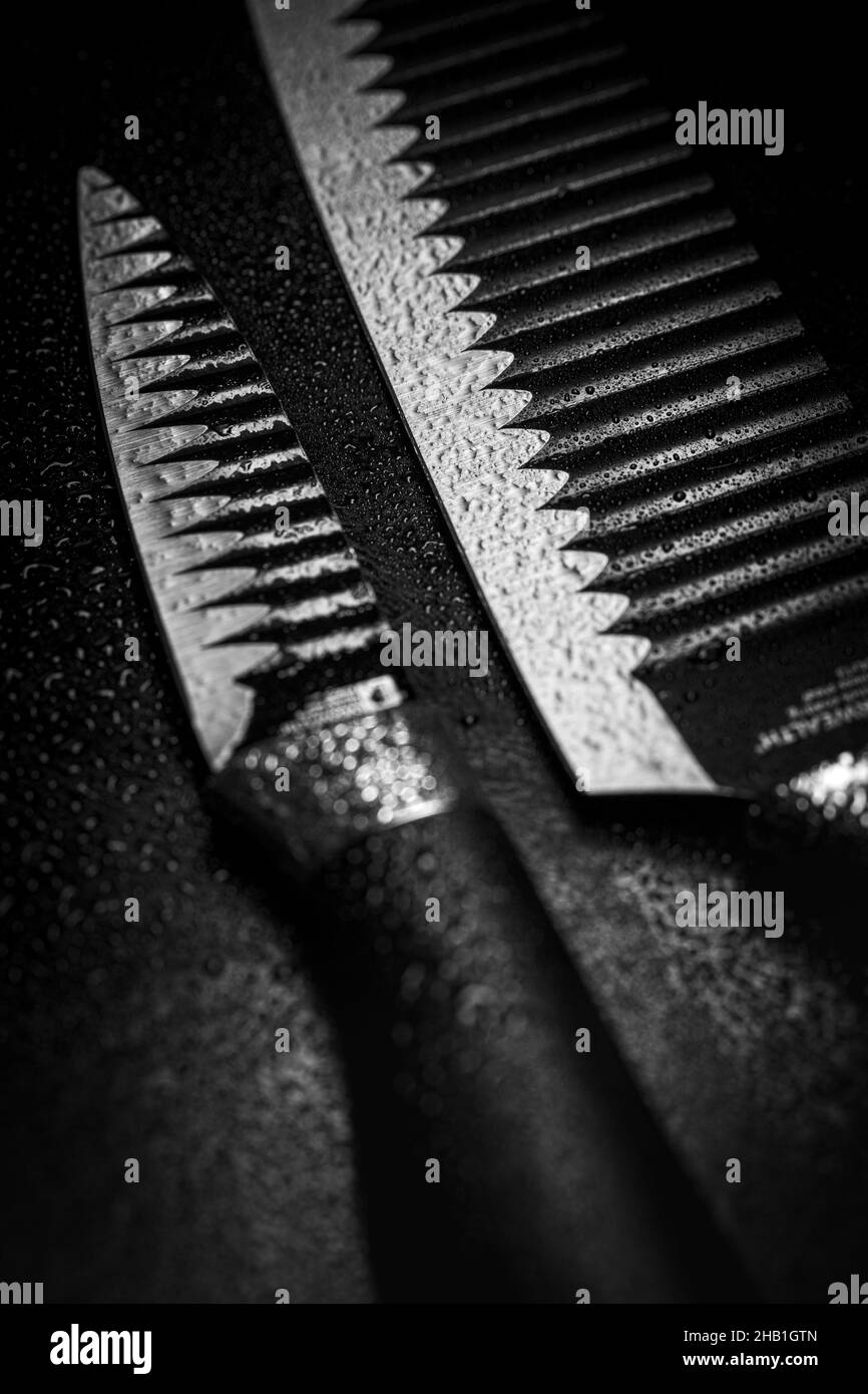 Primo piano verticale dei coltelli bagnati su sfondo nero. Foto Stock