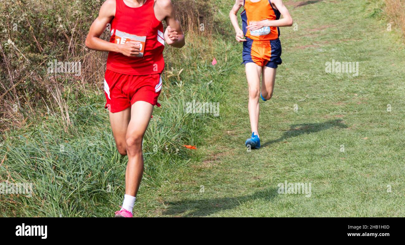 Due ragazzi delle scuole superiori una corsa durante un 5K a Bowdoin Park su un campo di erba ben curato in discesa. Foto Stock