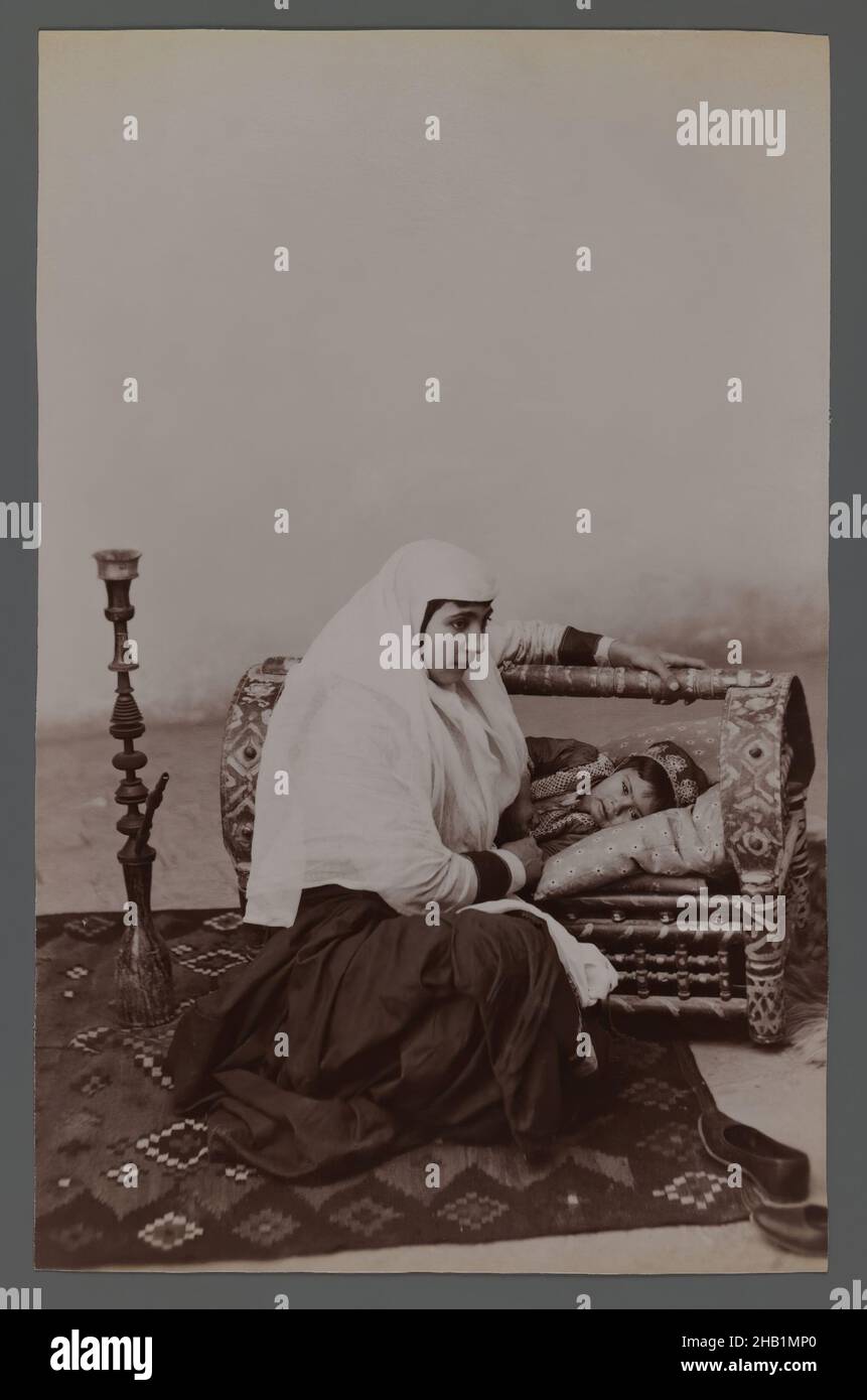 Donna che dondolava la culla del bambino, una delle 274 fotografie d'epoca, fotografia d'argento albume, fine 19th-inizio 20th secolo, Qajar, periodo Qajar, 8 3/16 x 5 1/4 in., 20,8 x 13,3 cm, 19th secolo, bambino, culla, culla decorata, Hijab, hookah, Iran, lifestyle, Medio Oriente, Madre, madre e bambino, Persia, tappeto persiano, fotografia, figlio, velo Foto Stock