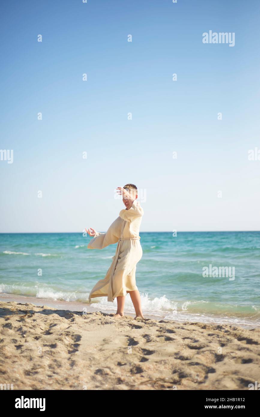 Un ragazzo in una mussola sta ballando sulla riva del mare. Imbrogliando intorno. Foto Stock
