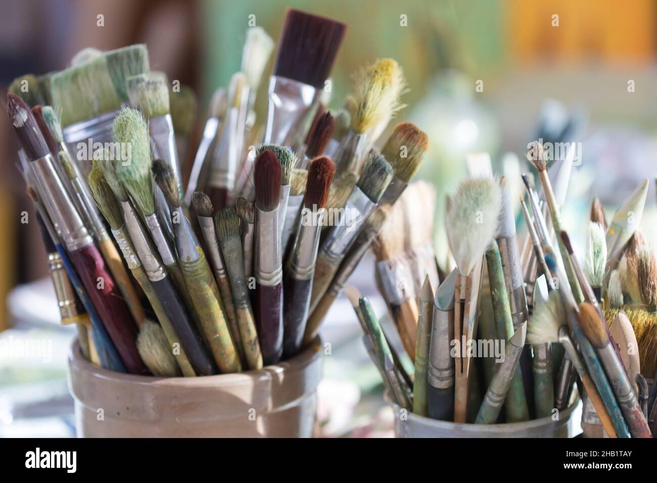 Selezione di pennelli dell'artista in contenitori di ceramica Foto Stock