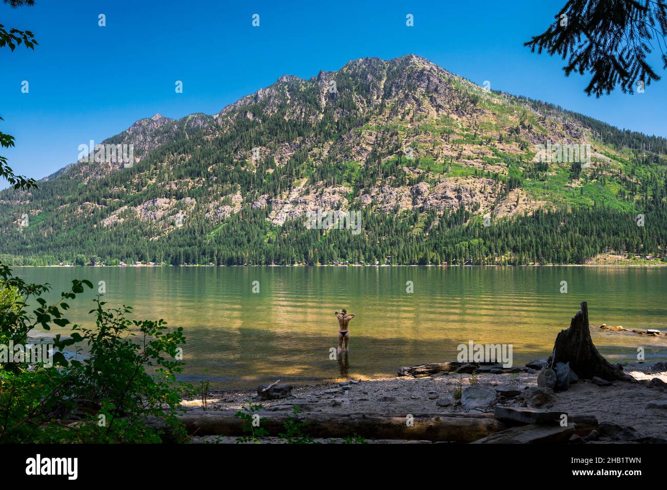 Donna che indossa un bikini in piedi in un lago nelle cascate Foto Stock