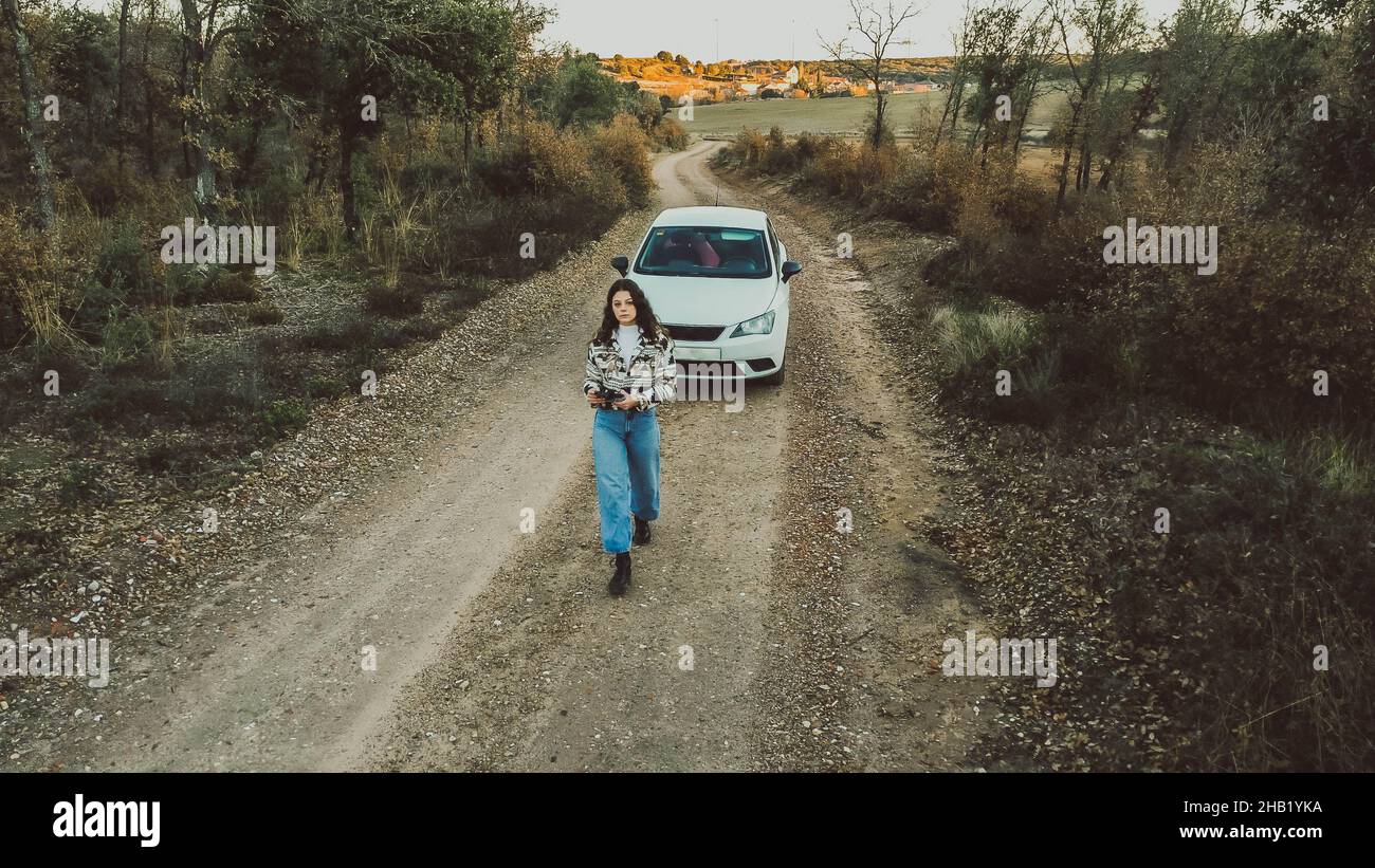 vista dall'alto della donna di fronte a un'auto bianca tra boschi Foto Stock