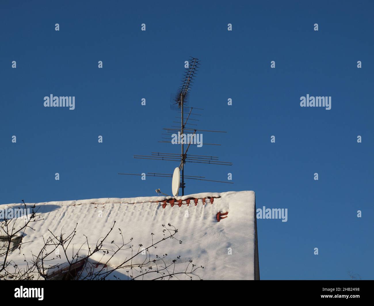 Il tetto è coperto di neve con varie antenne contro il cielo blu. Foto Stock