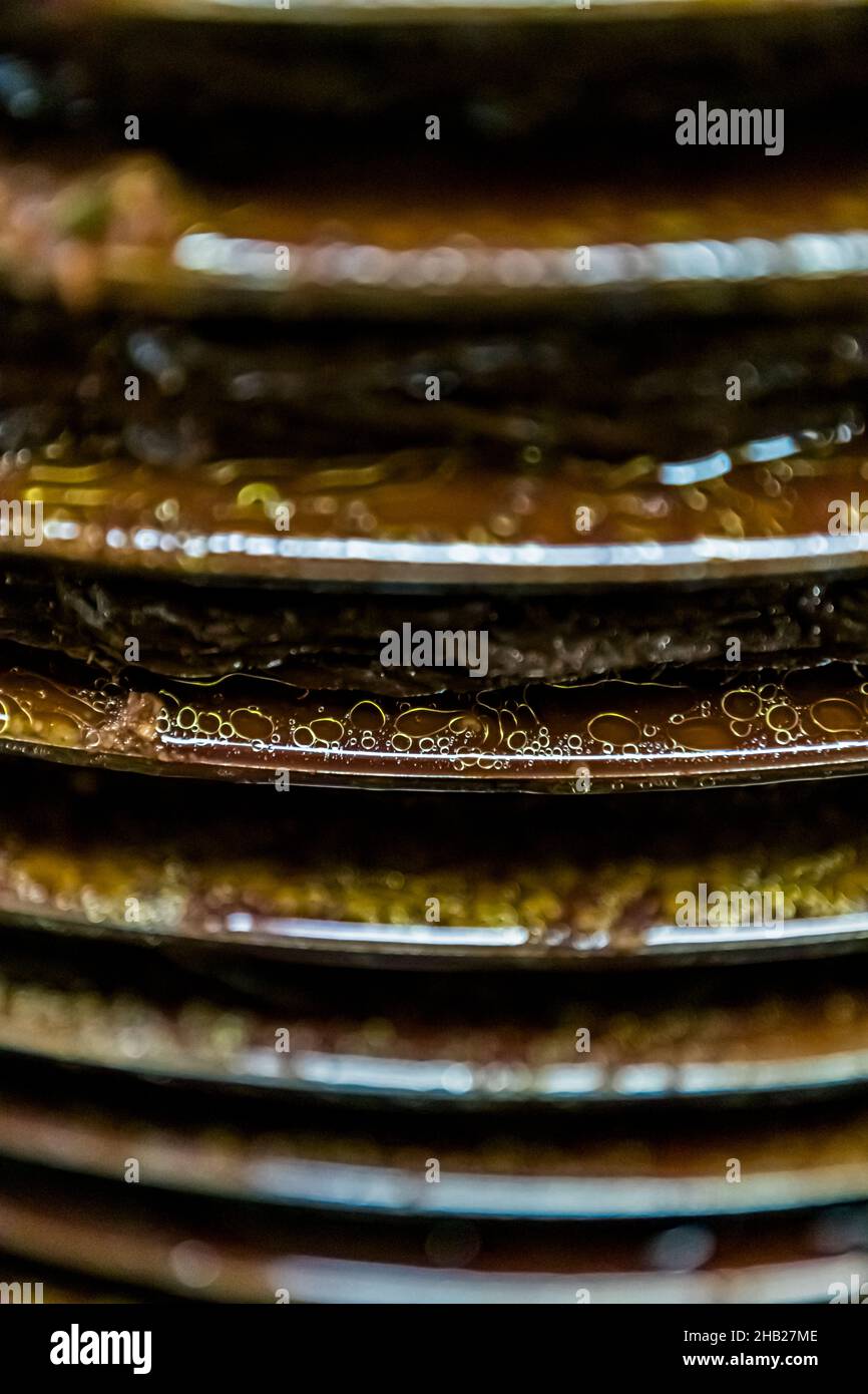 L'olio d'oliva dorato si insinua tra i tappetini di pressatura nella frantoio Moulin de Saint-Cassien a Draguignan, nel dipartimento di Var, Francia, mentre l'acqua di frutta più pesante defluisce insieme ad esso; i due liquidi vengono separati l'uno dall'altro dopo la pressatura. Foto Stock