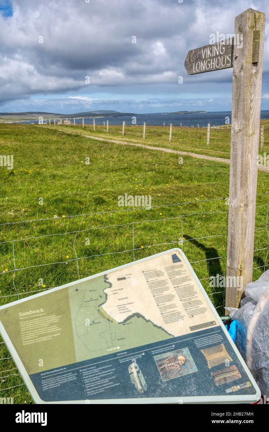 Informazioni turistiche e segno per il sito di uno scavato Vichingo Longhouse a Sandwick su Unst, Shetland. Foto Stock
