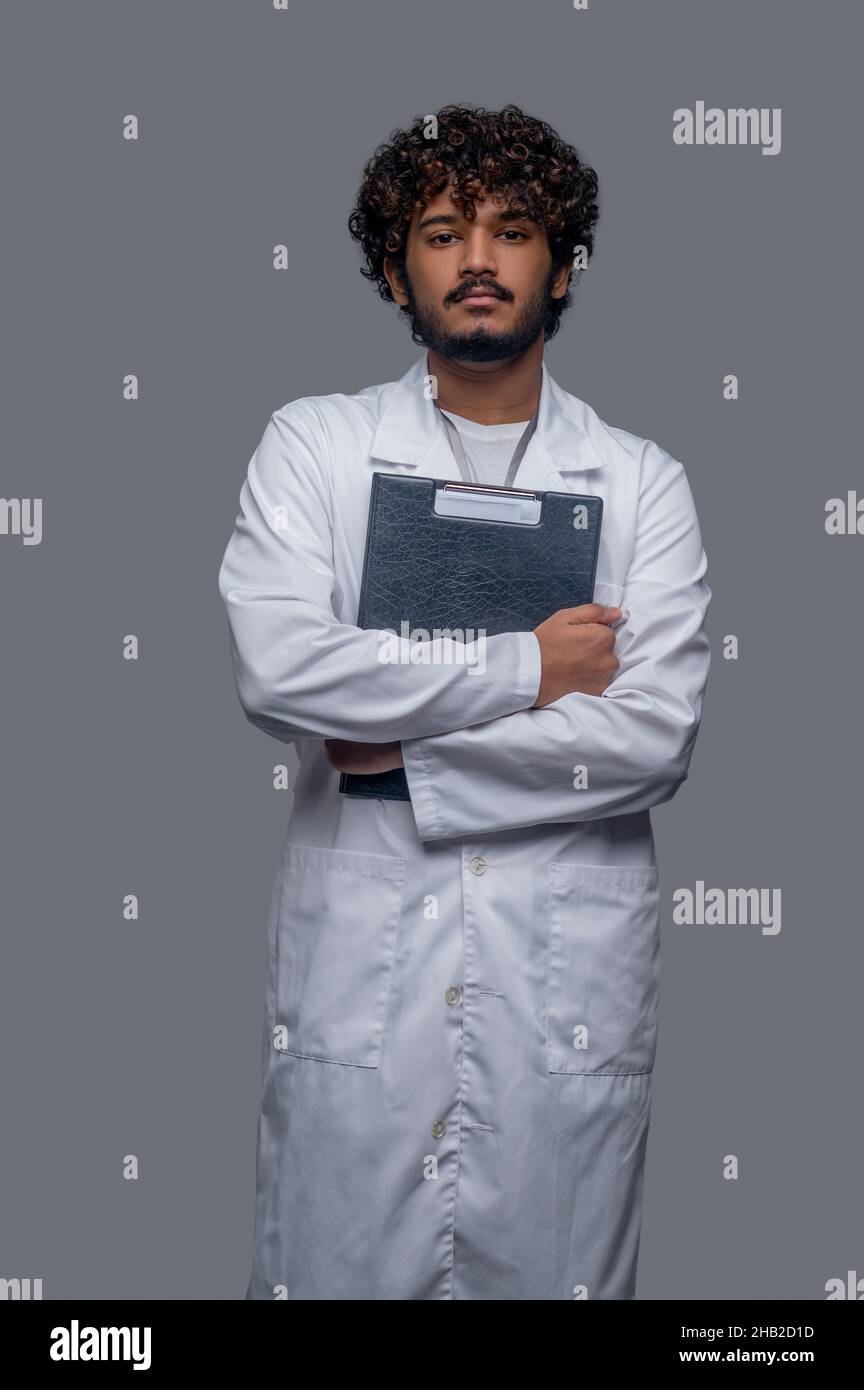 Medico giovane con documenti medici guardando avanti Foto Stock