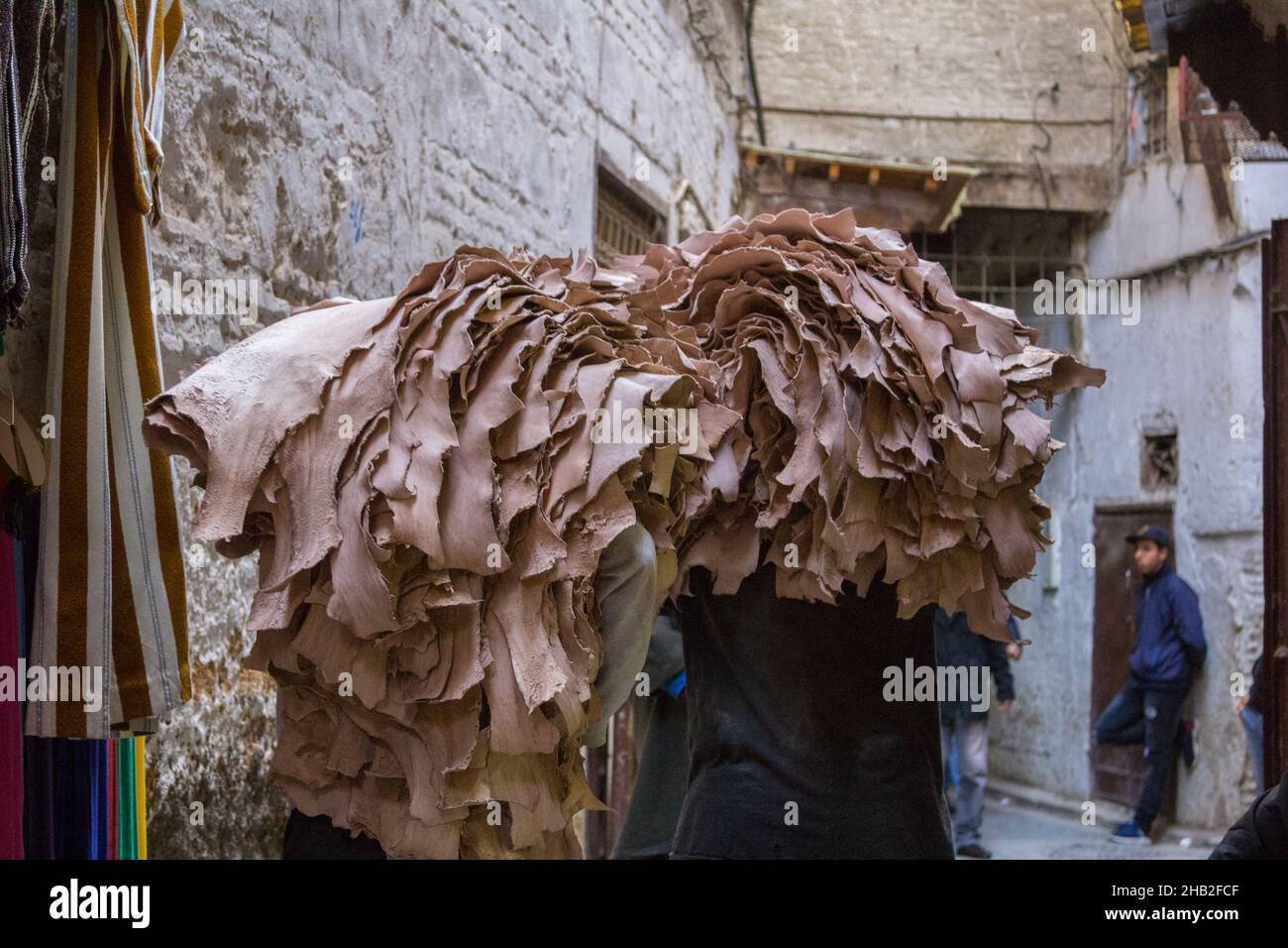 Fez, Marocco - Febbraio 23. 2019: Gente locale che trasporta la pelle grezza sul retro attraverso la stretta corsia in medina (centro storico) al mercato vicino a. Foto Stock