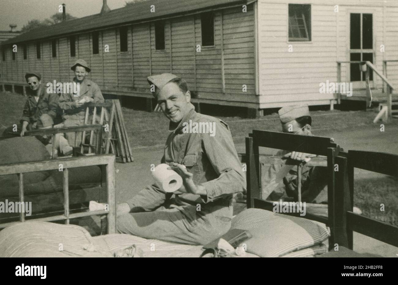 Antica fotografia del c1950, soldato dell'esercito post-WWII che tiene carta igienica fuori dalle caserme. Il gruppo di soldati sta rimuovendo o installando le finestre nell'edificio. Posizione esatta sconosciuta, Stati Uniti. FONTE: STAMPA FOTOGRAFICA ORIGINALE. Foto Stock