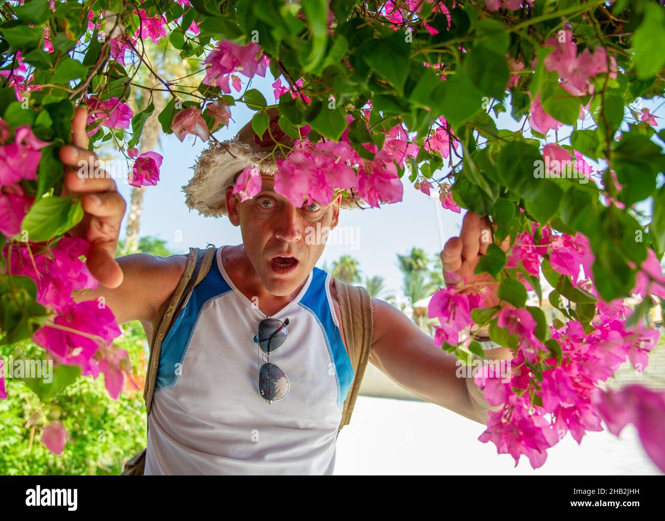 Uomo di 45-50 anni di costruzione atletica con uno zaino in Hurgada Egitto coperto di fiori rosa.concetto: Trekking e trekking. Foto Stock
