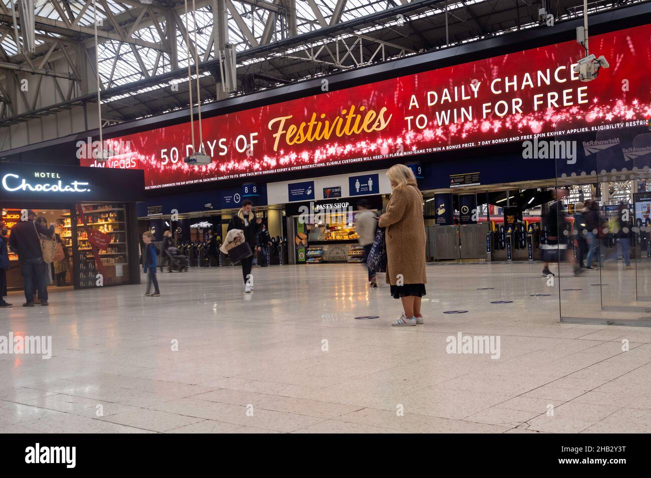 La gente alla stazione ferroviaria di Waterloo, Londra Regno Unito in dicembre - viaggiatori a lunga esposizione che precipitano il concetto di hurrying Foto Stock