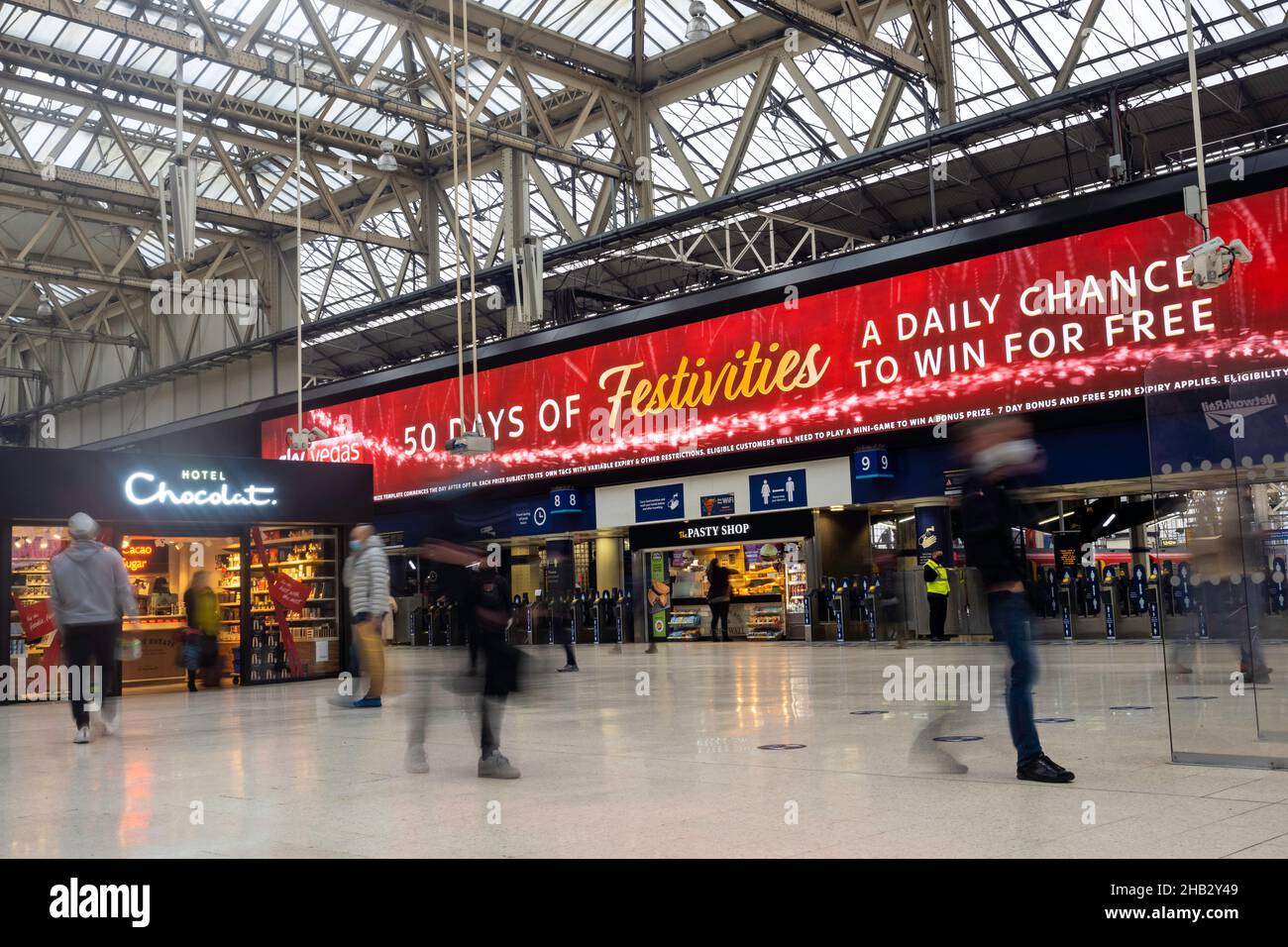 La gente alla stazione ferroviaria di Waterloo, Londra Regno Unito in dicembre - viaggiatori a lunga esposizione che precipitano il concetto di hurrying Foto Stock
