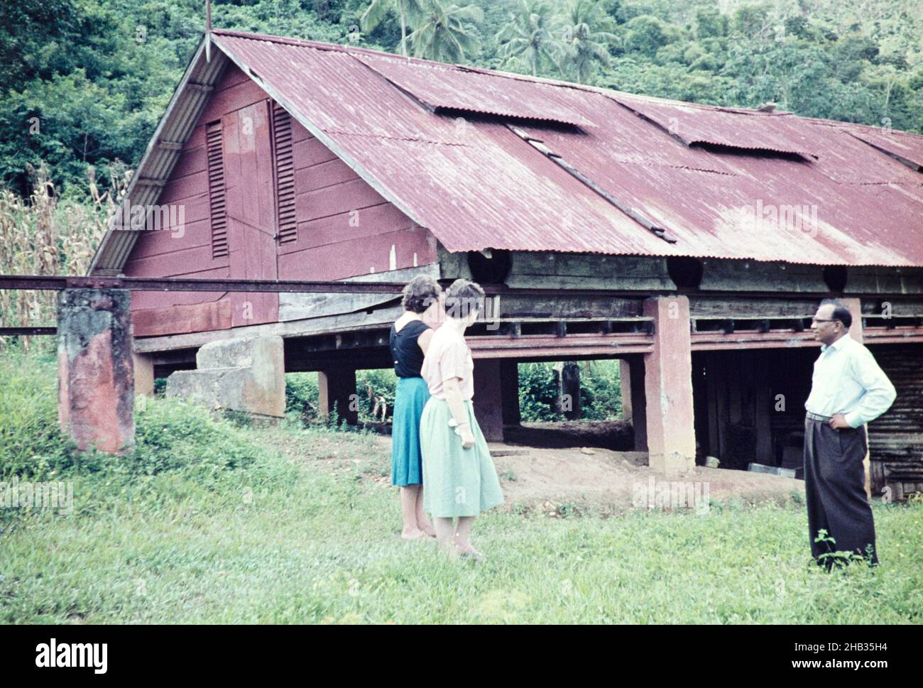 Due donne britanniche che visitano il capannone di essiccazione del cacao con il sig. Khan, direttore dell'azienda agricola, Trinidad c 1962 rurale Foto Stock