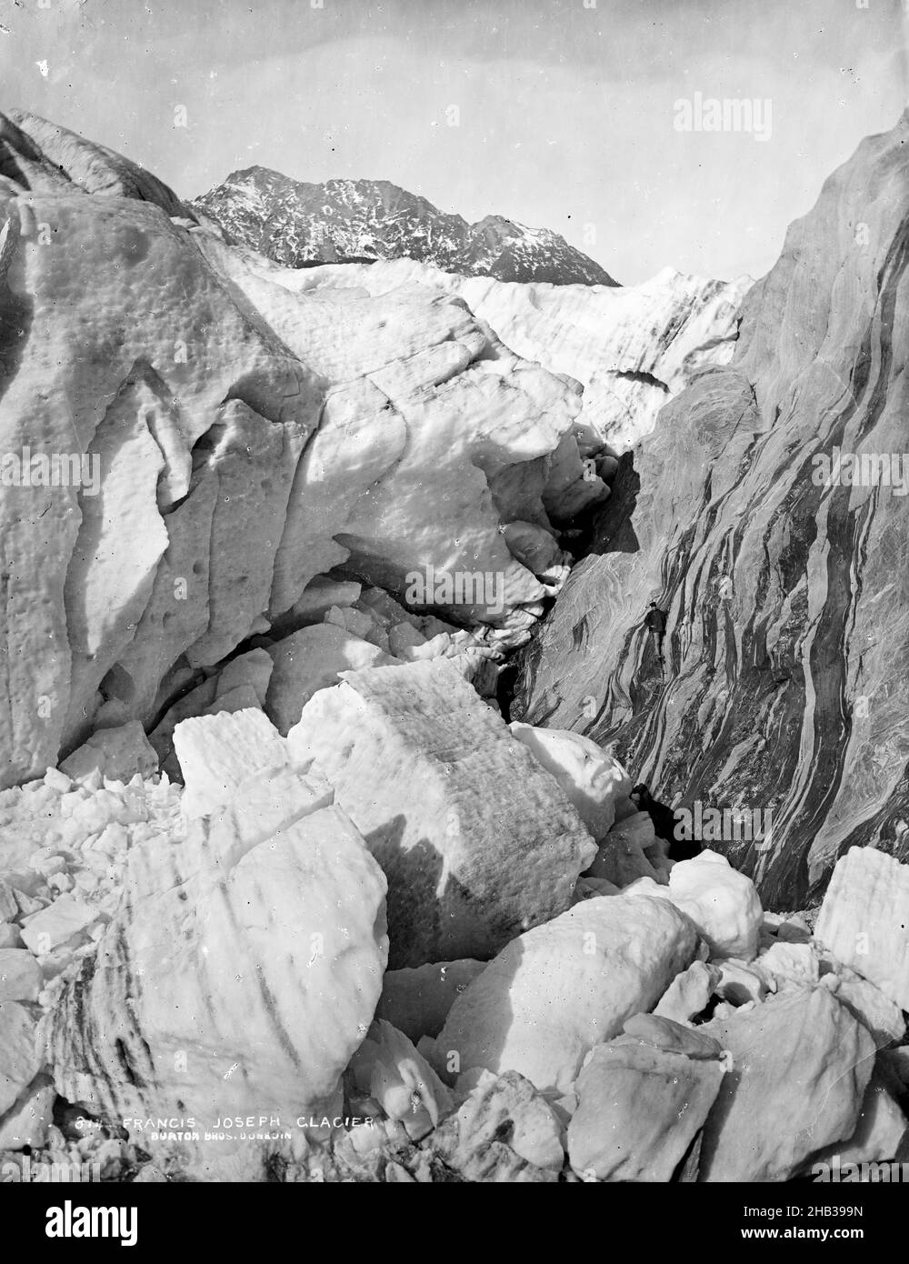Francis Joseph Glacier, studio Burton Brothers, studio fotografico, 1870s, Dunedin, Processo di collodio umido, vista ravvicinata di grandi pezzi di ghiaccio. C'è una ripida sezione di roccia sulla destra con un uomo in piedi su una scala a corda Foto Stock