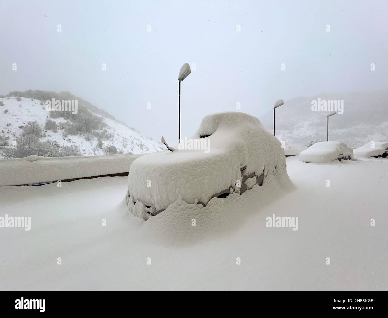 SUV coperto di neve in un parcheggio in una giornata invernale nevosa Foto Stock