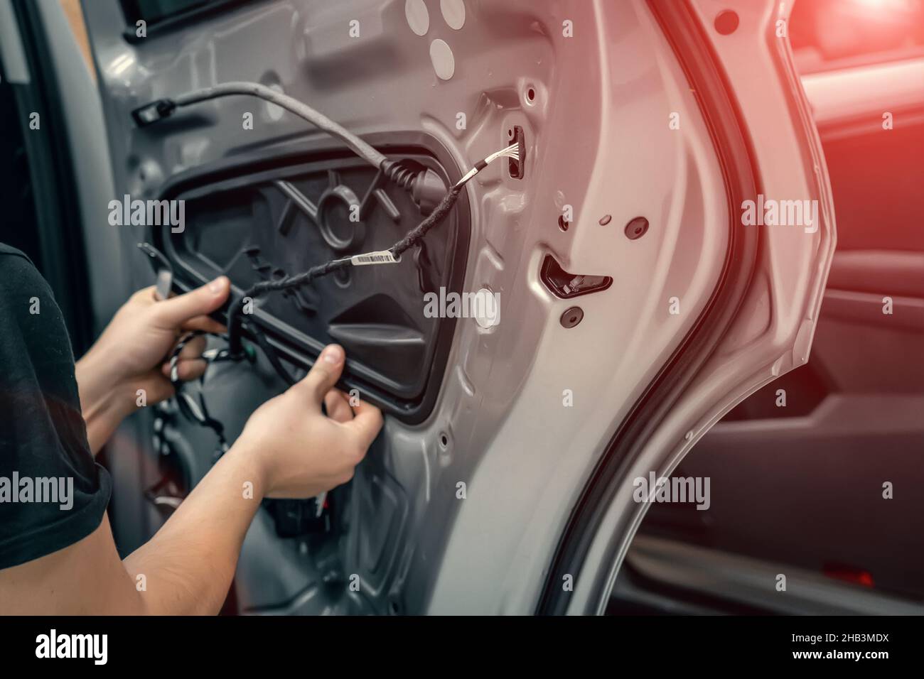 L'addetto all'assistenza auto smonta la porta dell'auto per una riparazione ravvicinata. Foto Stock
