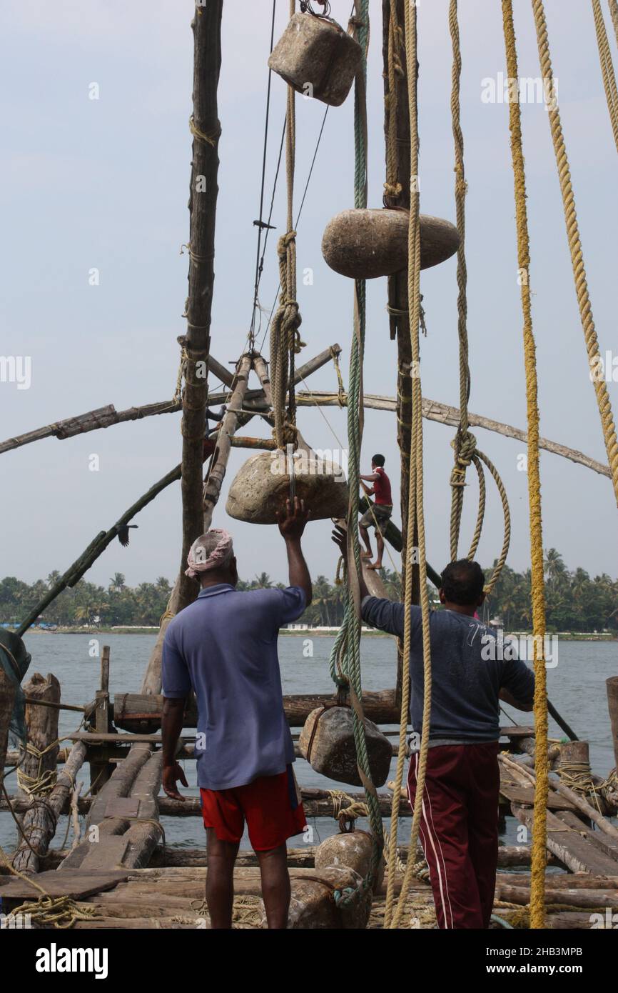 Pescatori con reti da pesca cinesi a sbalzo a Kochi Kerala, India Foto Stock