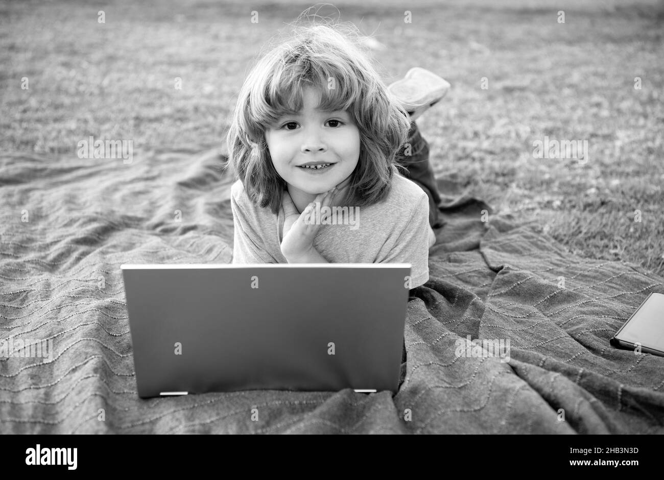 Scopri la formazione online. Bambino ragazzo usa il laptop naturale all'aperto. Utilizzo della tecnologia di apprendimento Foto Stock