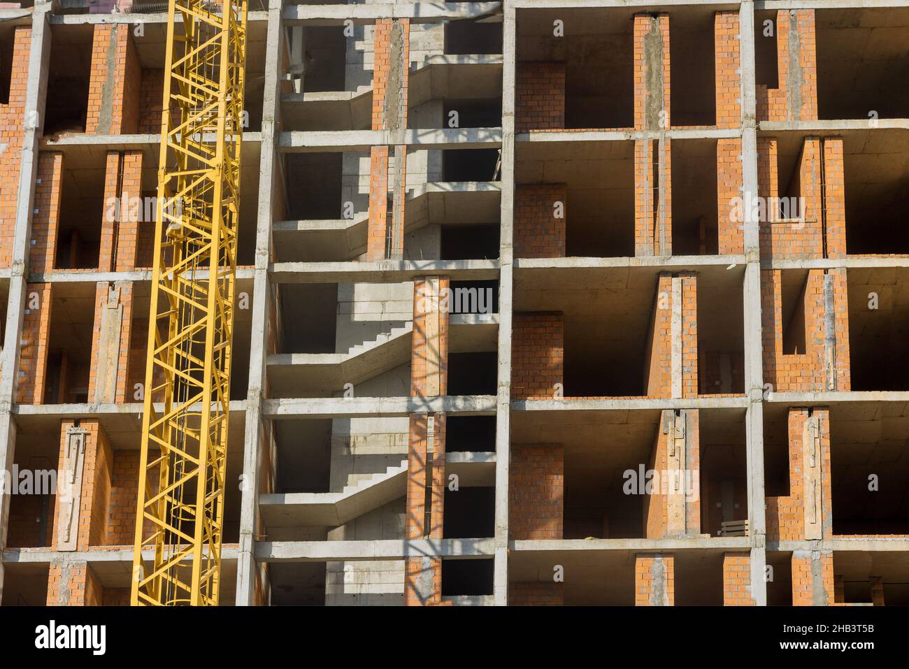 Lungo l'edificio in corso sono in corso lavori di costruzione di un edificio ad appartamenti a più piani Foto Stock