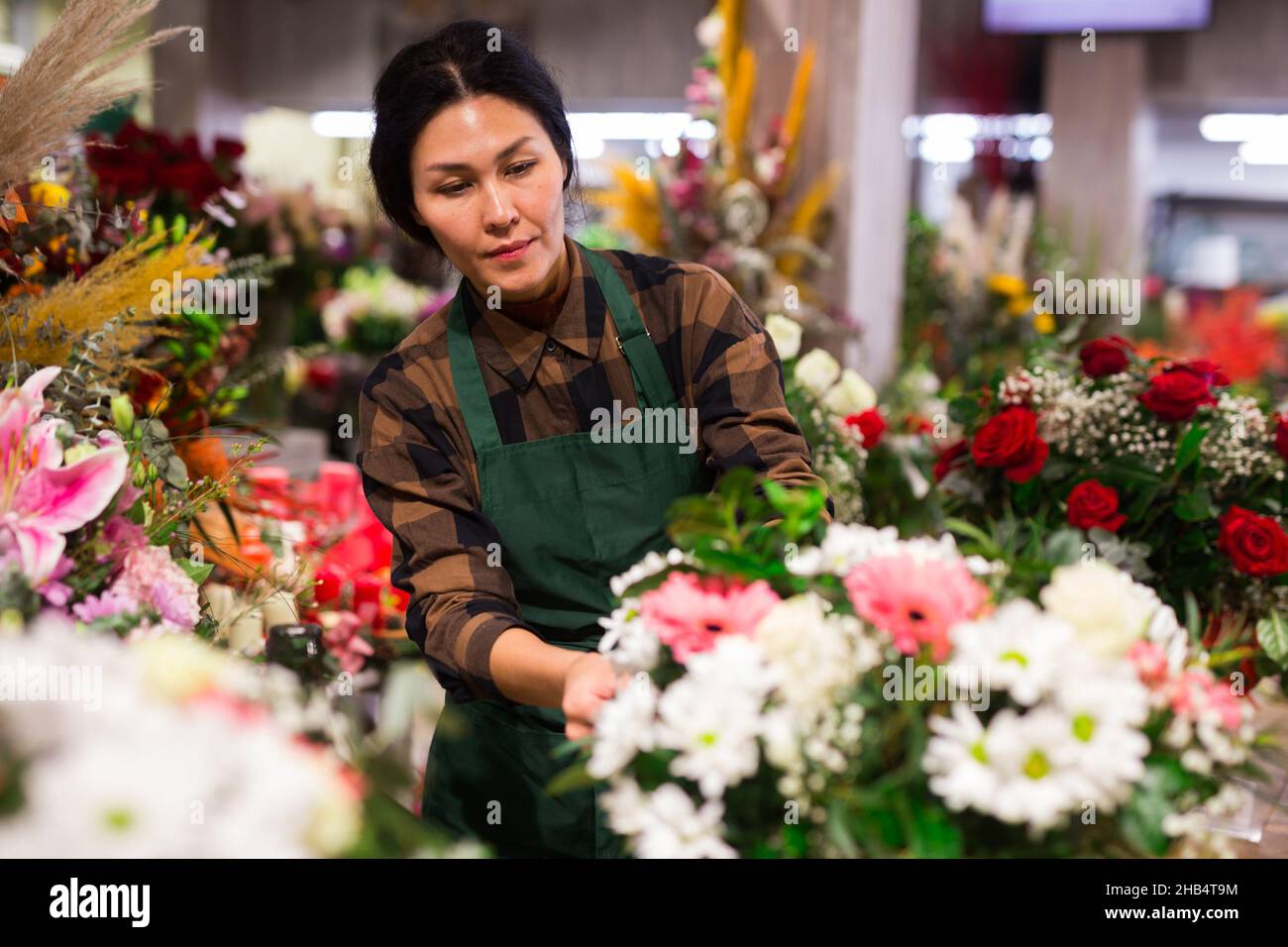 Fiorista femminile asiatico esamina i mazzi in un negozio di fiori Foto Stock