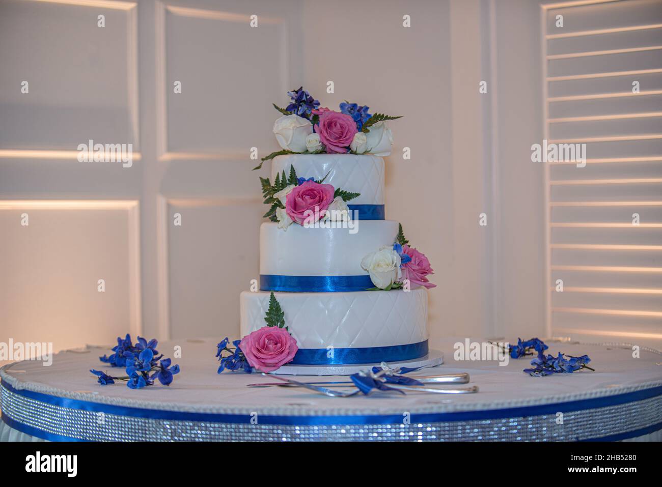 Splendida torta nuziale con decorazioni rosa e bianco e nastro blu Foto Stock