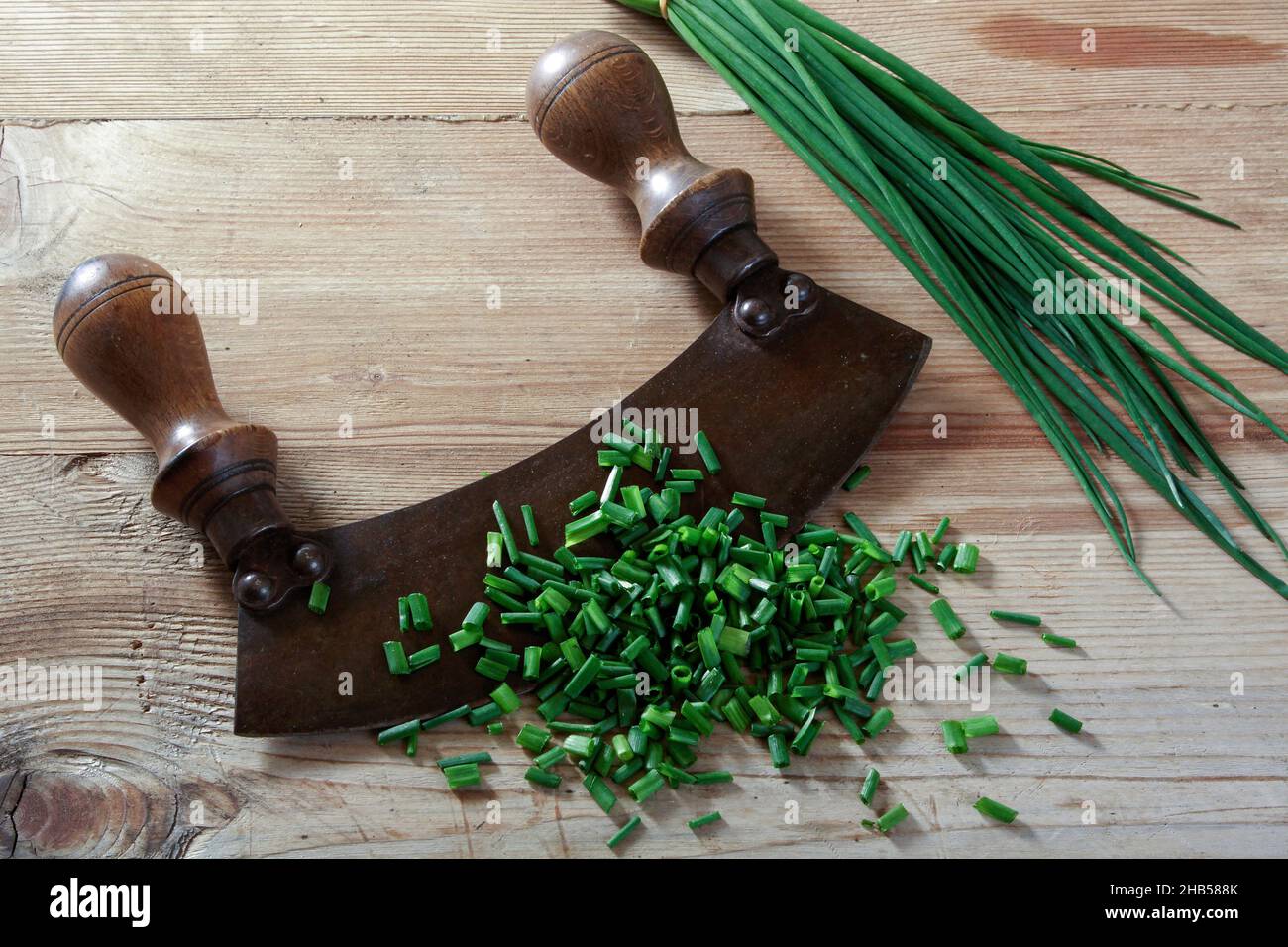 vecchio coltello per tritare con porri e prezzemolo su sfondo di legno Foto Stock