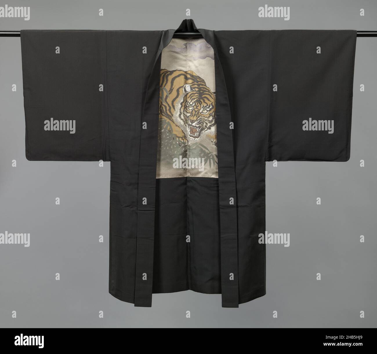 Giacca uomo, hauri uomo con tigre, luna e bambù, Haori per un uomo con una decorazione sul rivestimento di una tigre che appare minaccioso da dietro bambù sotto una luna di mezzaluna nuvolosa. Seta nera lucida (habutae) con decorazione in tessuto broccato. Cresta singola famiglia (mon) di foglia di quercia stilizzata (kashiwa)., costruttore: anonimo, Giappone, 1920 - 1940, seta, altezza 131 cm x larghezza 103 cm Foto Stock