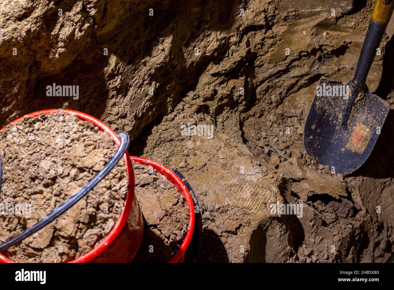 Scavando manualmente un foro nel terreno con una pala zaffatrice, scaricando il terreno con le benne Foto Stock