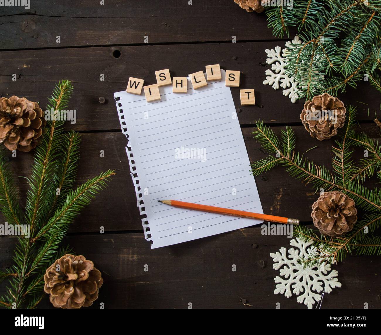 lista dei desideri di natale con penna scritta con lettere di legno e decorazioni di natale su spazio di legno marrone scuro per il testo Foto Stock