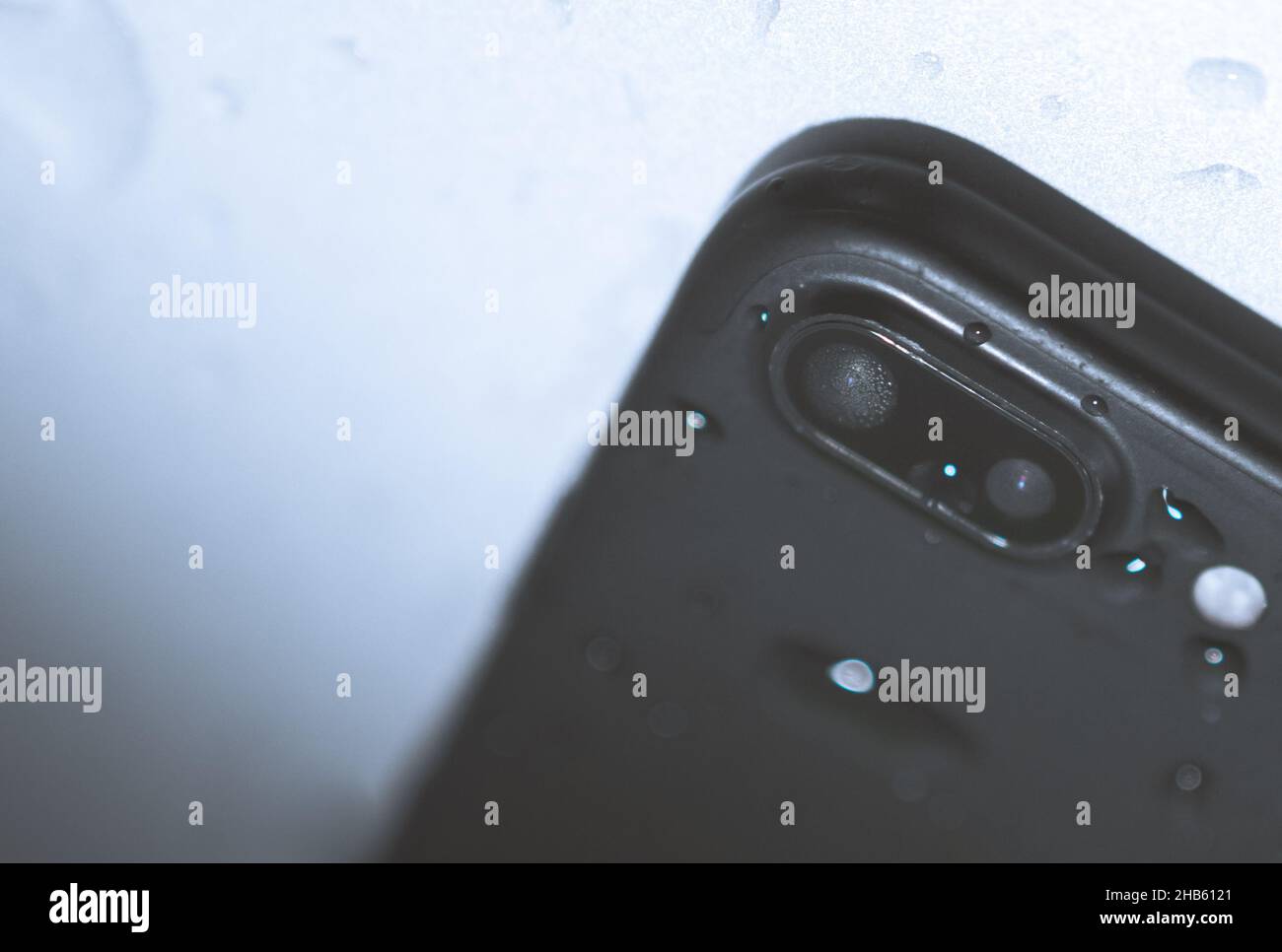 Primo piano dell'obiettivo nero della fotocamera dello smartphone con acqua all'interno e lit sul retro. Parte interna concetto di danni causati dall'acqua. Immagine vuota sapce. Foto Stock