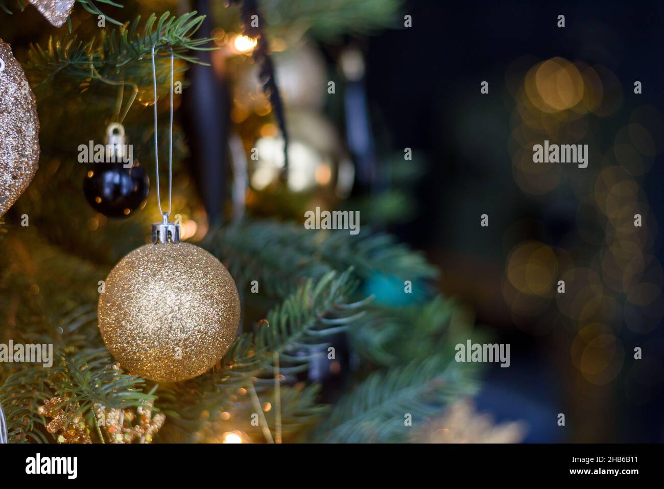 Decorazione dorata di Natale bauble su albero con luci Foto Stock
