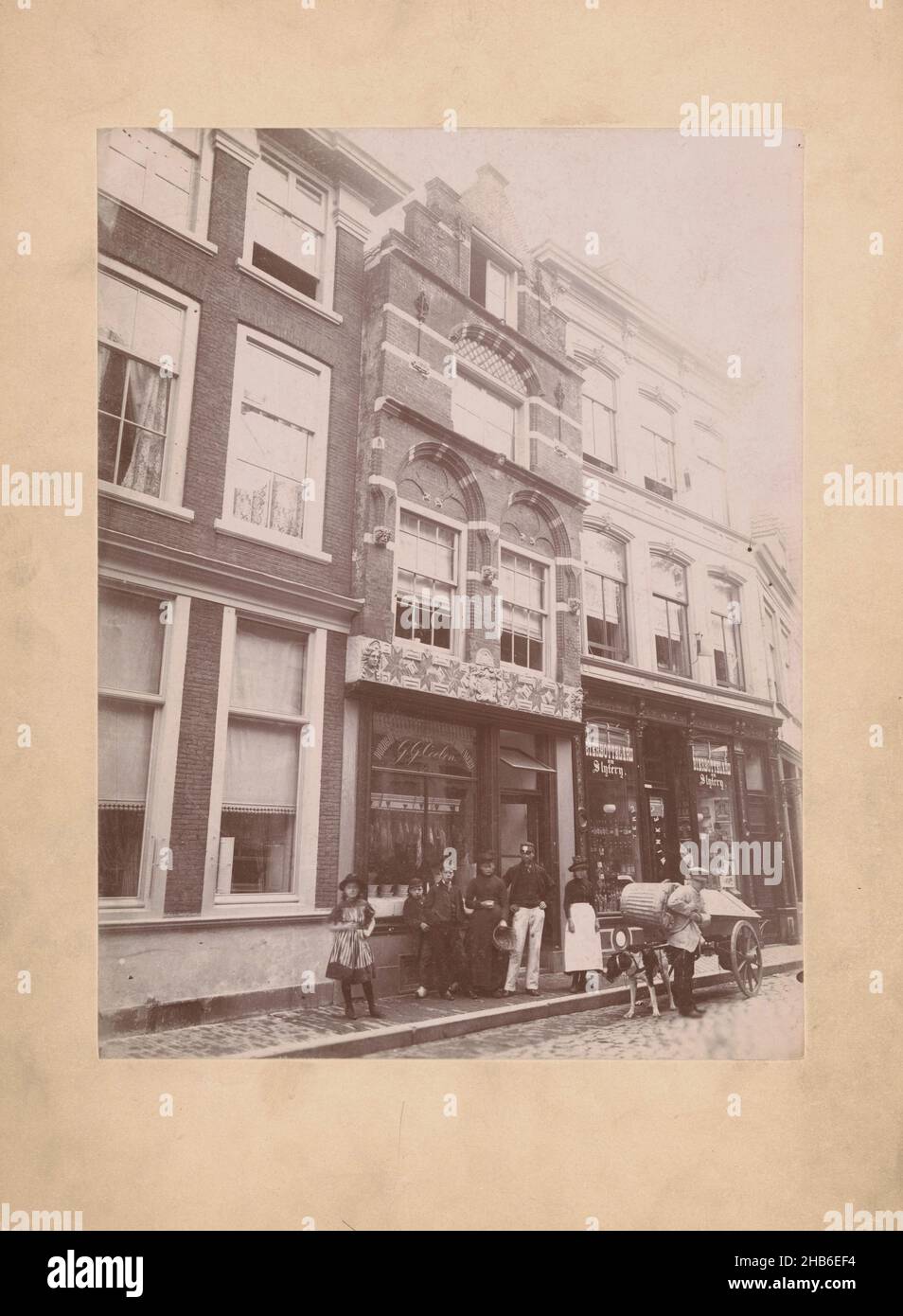 Vista della costruzione Steegoversloot 9 a Dordrecht con un gruppo di persone e un cane cart, A.J.M. Mulder (attribuito a), Dordrecht, c. 1896 - prima del 1918, cartone, supporto fotografico, altezza 232 mm x larghezza 176 mm Foto Stock
