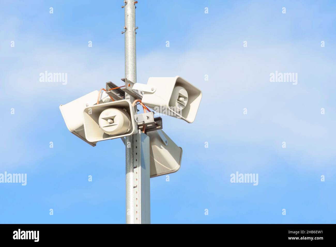 Diversi altoparlanti su palo, due altoparlanti per il sistema di comunicazione al pubblico su sfondo blu cielo Foto Stock
