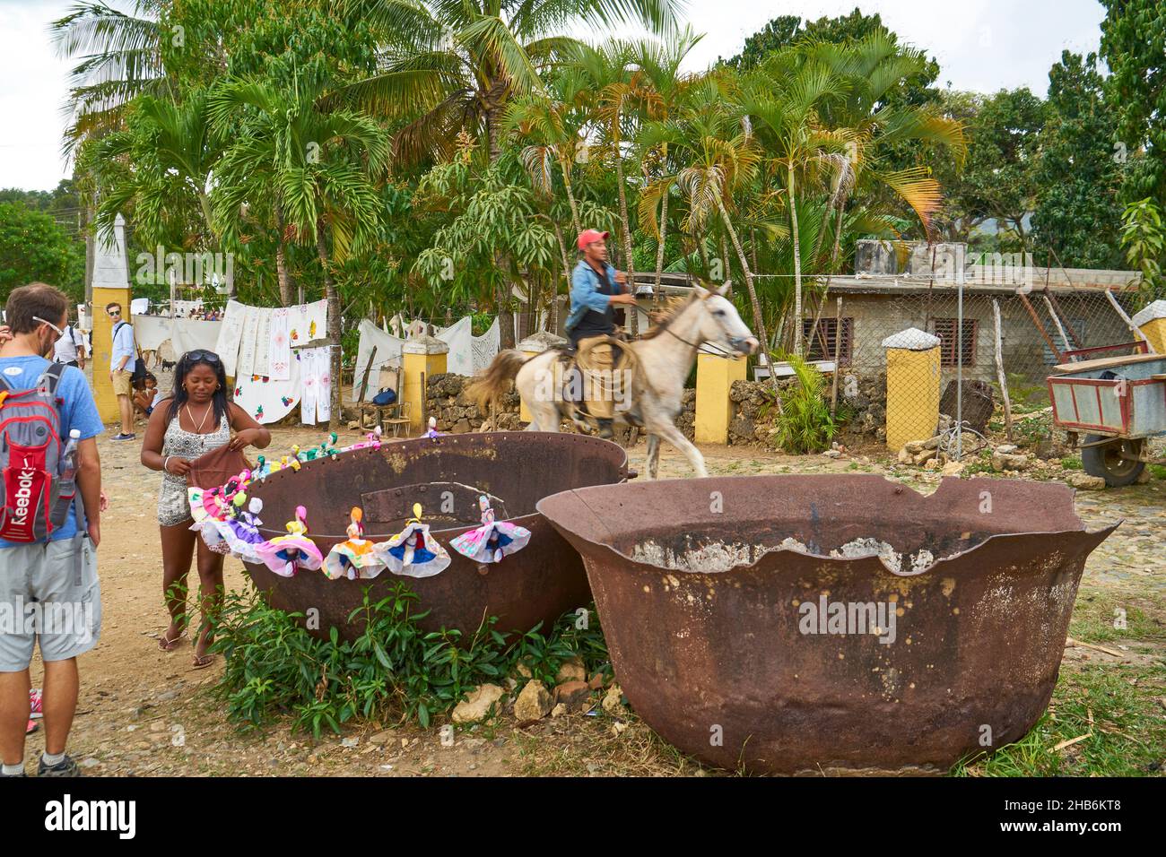 L'artigiano decora le sue bambole fatte a mano sul bordo di vecchie ciotole precedentemente usate per bollire il succo di canna da zucchero, Cuba, Valle de los Ingenios, Sancti Foto Stock