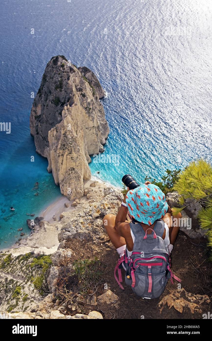 Escursionista ad alture vertiginose fotografando la roccia costiera di Mizithres, Grecia, Isole IONIE, Zante, Kericho Foto Stock