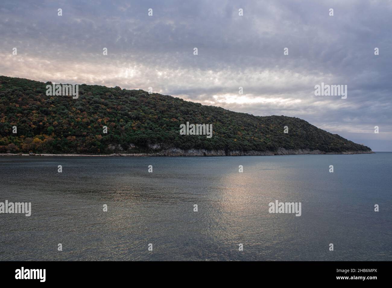 Bellissimo scatto di scogliere boscose sotto un cielo blu nuvoloso durante il tramonto Foto Stock