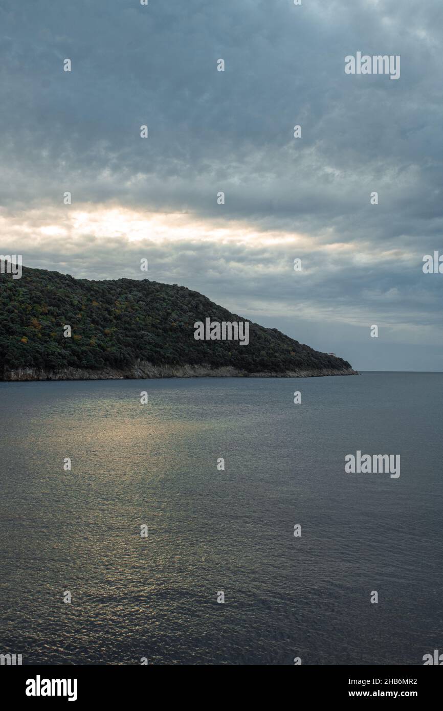 Bellissimo scatto di scogliere boscose sotto un cielo blu nuvoloso durante il tramonto Foto Stock