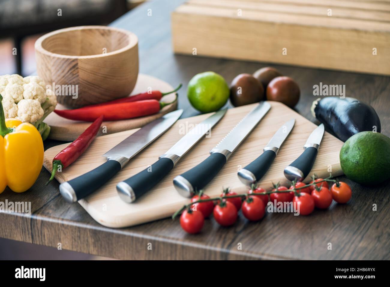 Chef Knifes su bordo di tritare in legno con verdure fresche sfondo. Concetto di cibo sano. Cibo vegetariano crudo Foto Stock