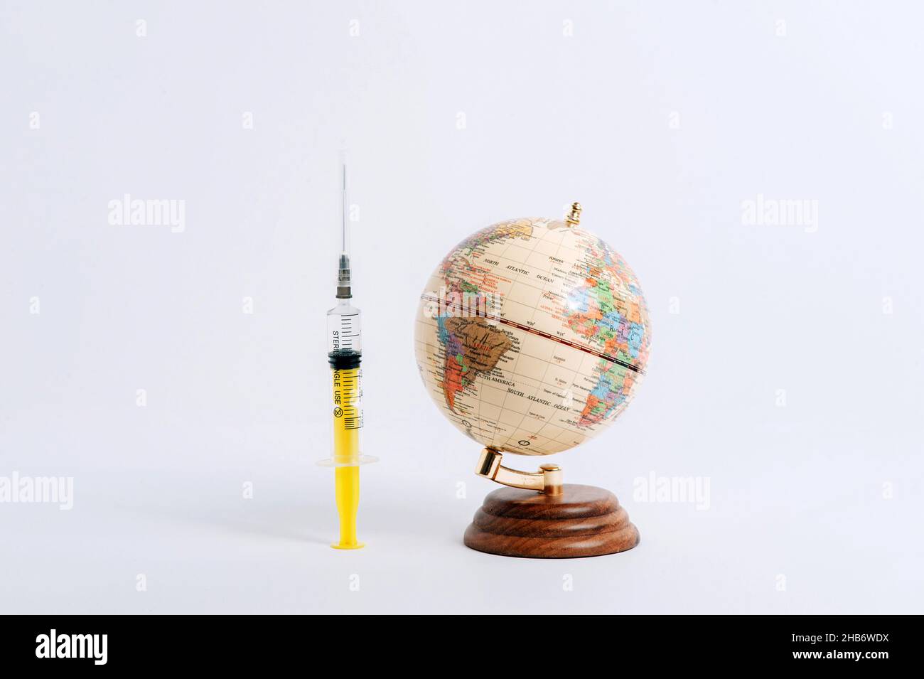 Il globo e la siringa su sfondo bianco. Il coronavirus 2020 disperazione nel mondo. Foto Stock