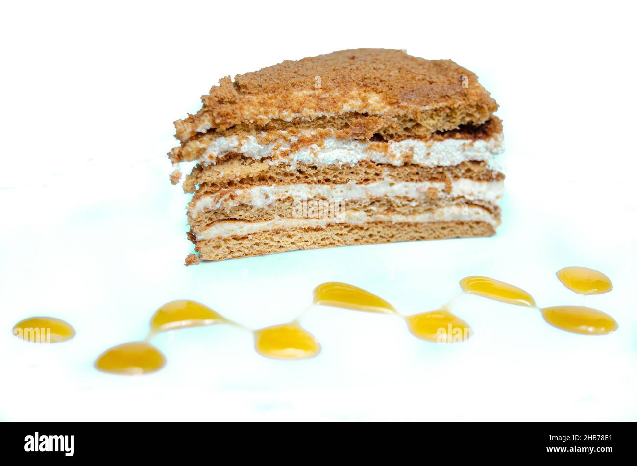 gocce di miele sul piatto, torta medovik isolare su bianco Foto Stock
