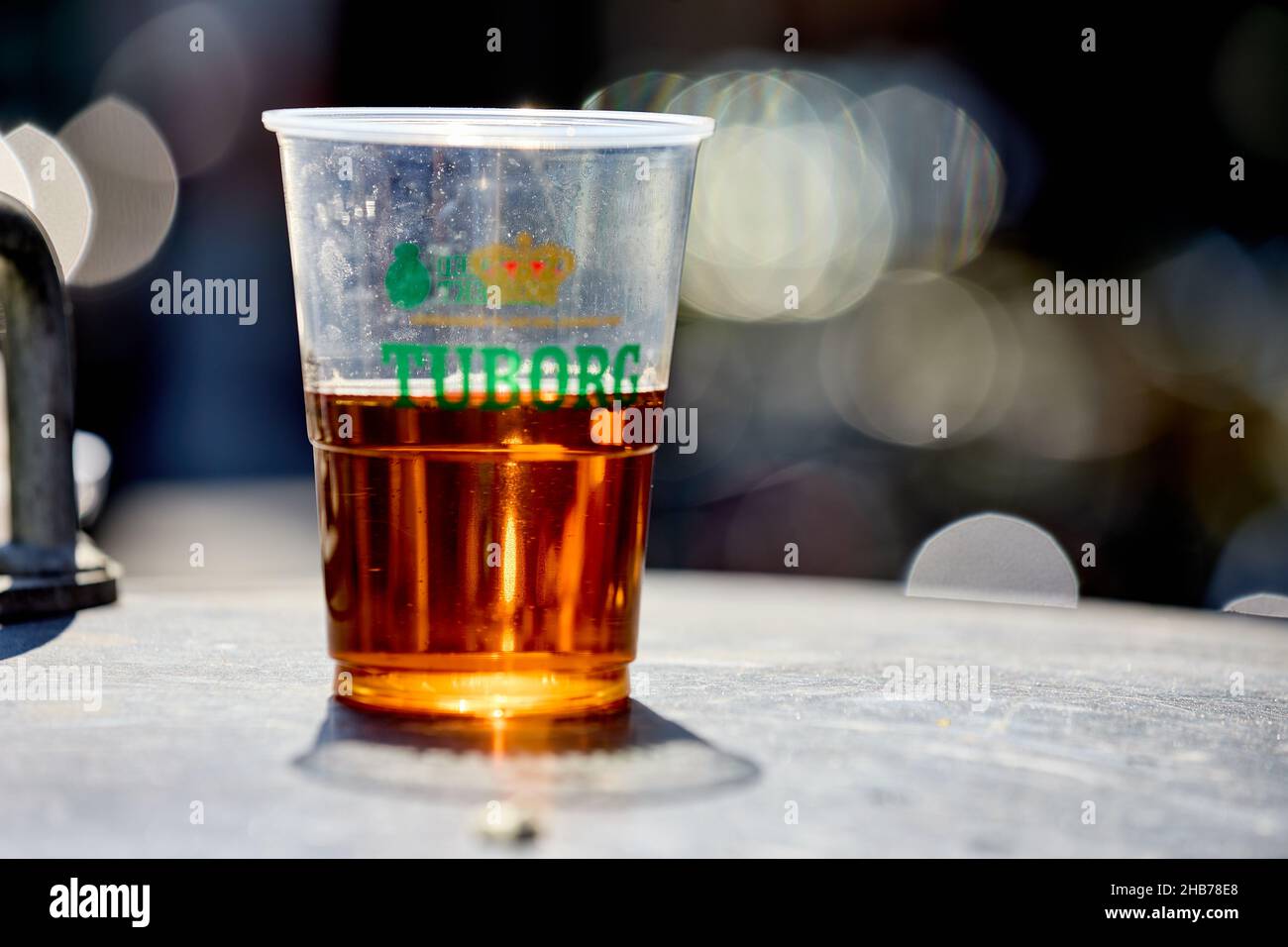 Tuborg, birra in un bicchiere di plastica con impronte digitali visibili, mezzo pieno Foto Stock