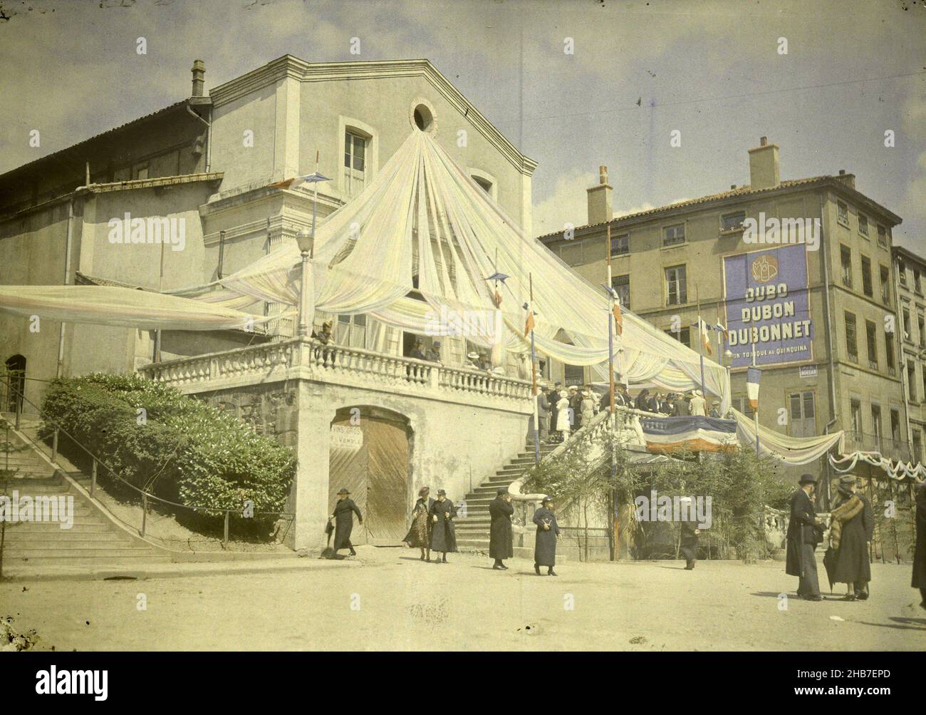 Scena stradale vicino al municipio decorato bandiera, con pubblicità per Ducoonnet, anonima, Francia, c.. 1935, altezza 129 mm x larghezza 177 mm Foto Stock