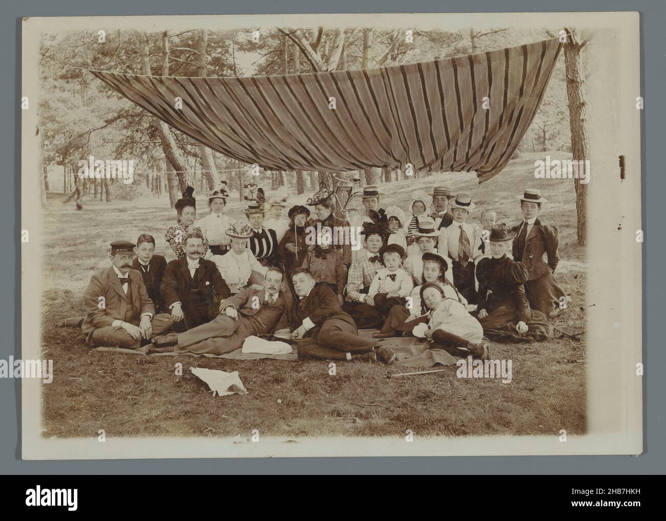 Ritratto di gruppo della famiglia Geertsema con Karel van den Berg e Frans e Poppie van den Berg e altri, seduti sull'erba nei boschi sotto una tenda a strisce, A.C.M. Geertsema, (cerchio di), Paesi Bassi, c.. 1900 - c. 1901, supporto fotografico, altezza 180 mm x larghezza 126 mm Foto Stock