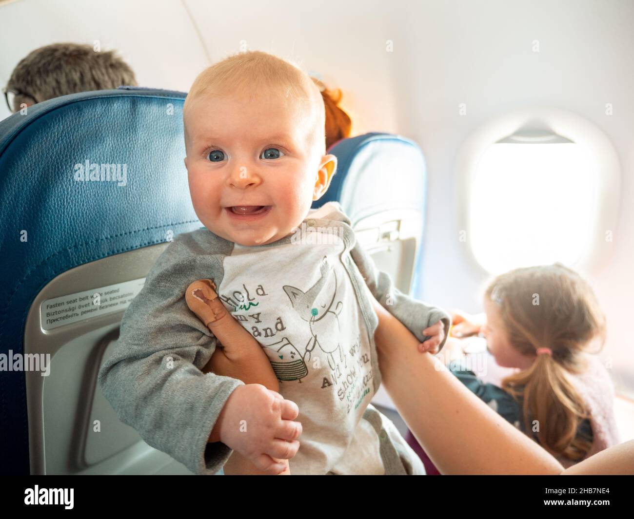 Volare con un felice sorridente bambino di quattro mesi a bordo di volo aereo passeggeri Foto Stock