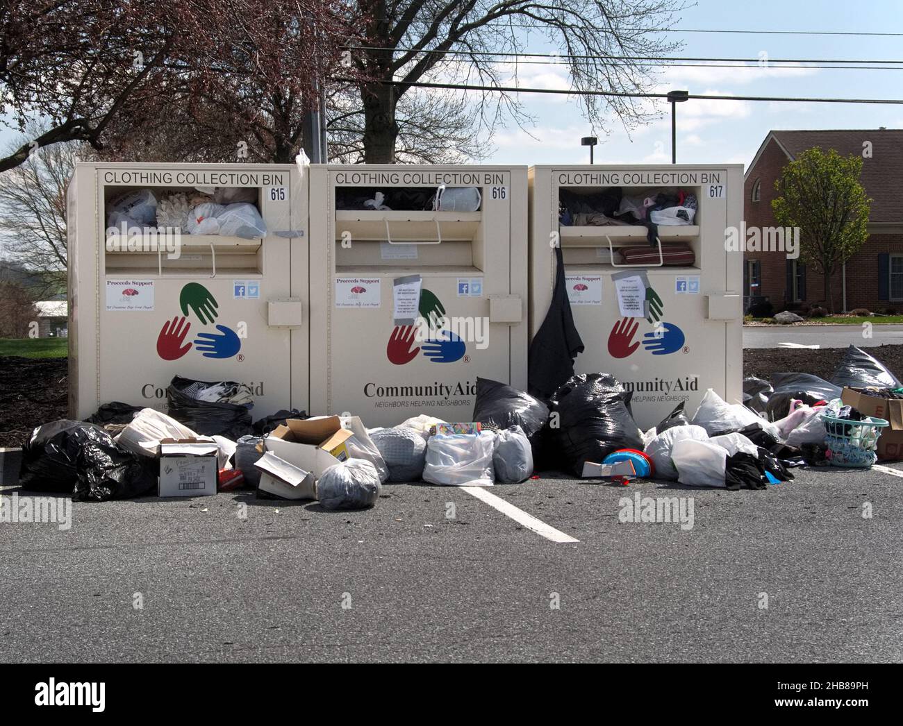 Straripante bidoni di donazione di abbigliamento con più borse a terra, in un centro commerciale locale a Manheim, Pennsylvania Foto Stock