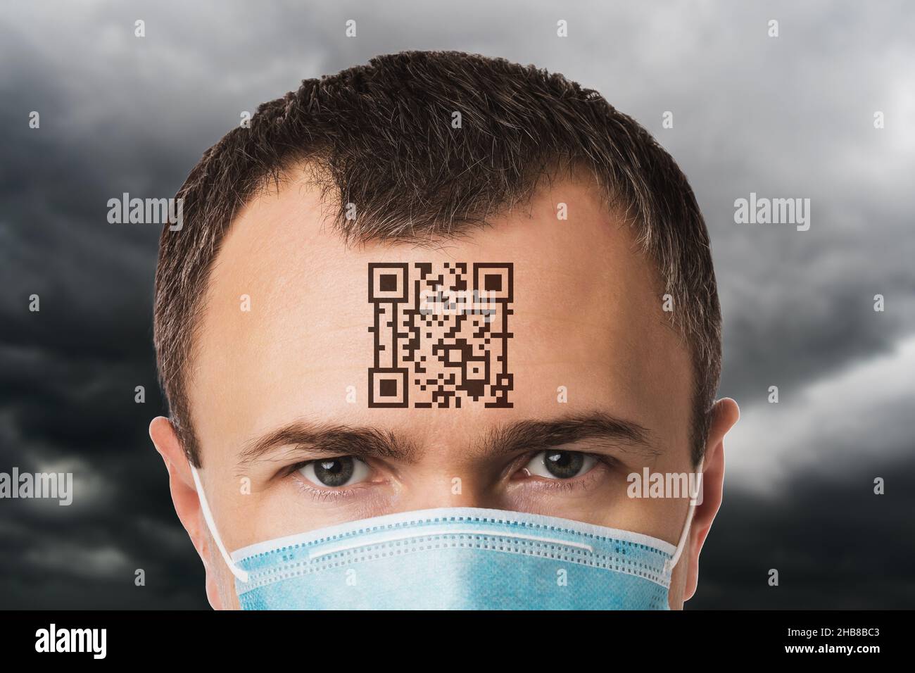 Un uomo in maschera con un codice QR sulla fronte, sullo sfondo di un cielo nuvoloso, un concetto sul tema di una prigione digitale a causa del coronavirus, Foto Stock
