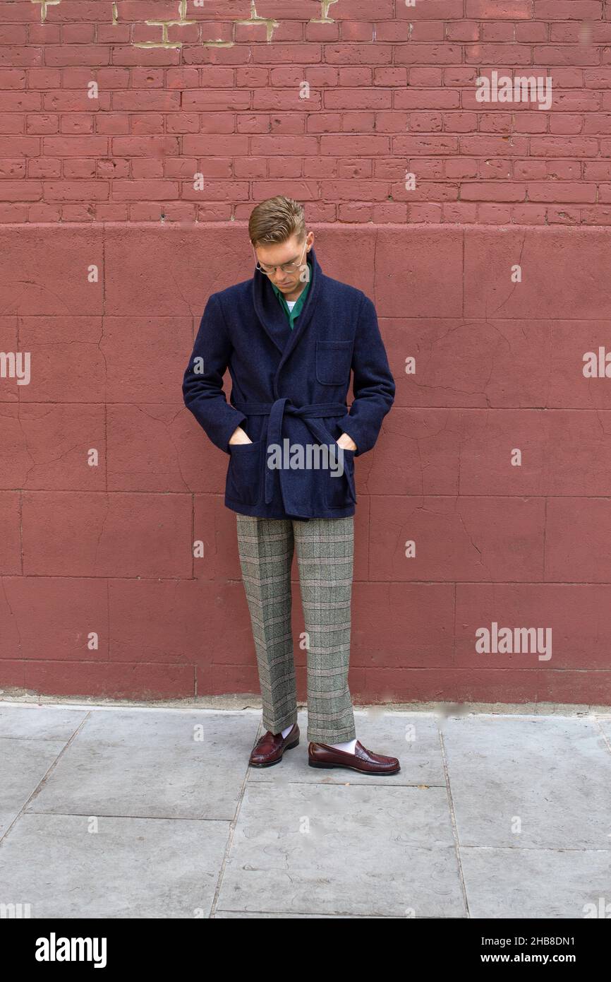 Giovane uomo che indossa abiti invernali per strada. Ragazzo giovane con loafer penny e cappotto elegante Foto Stock