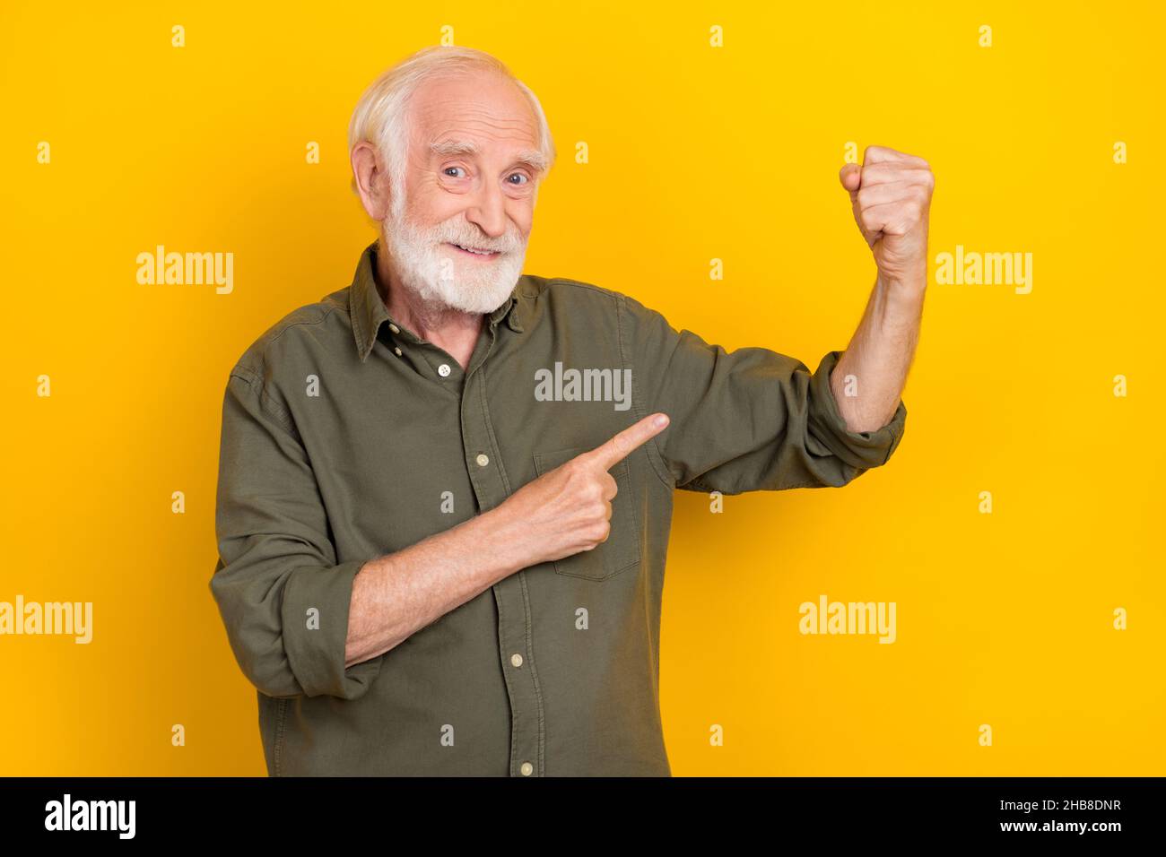 Foto di persona bella positiva indica dito braccio flettente bicipiti isolato su sfondo giallo Foto Stock