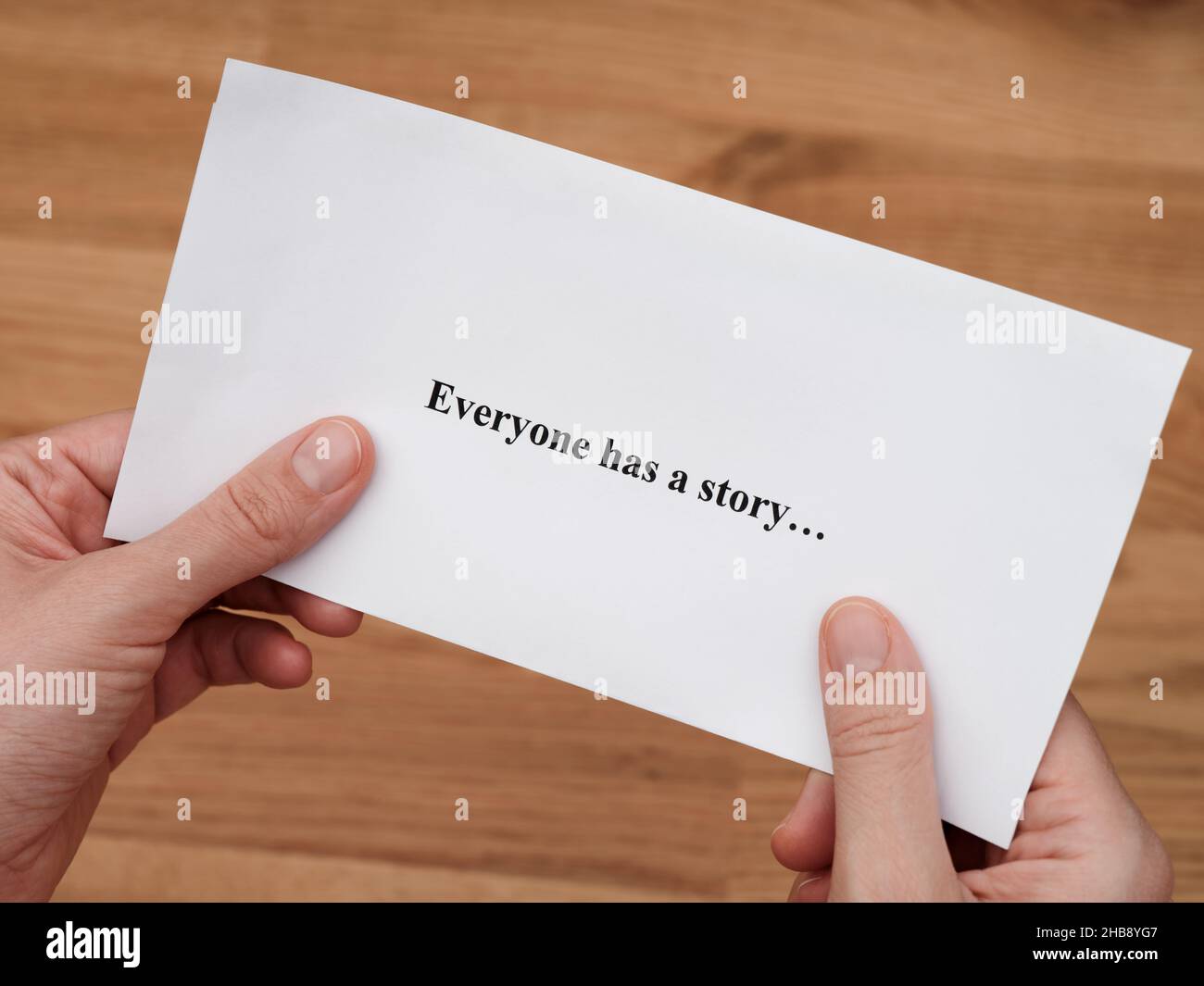 Una donna che tiene un pezzo di carta con le parole ognuno ha una storia scritta su di esso. Primo piano Foto Stock