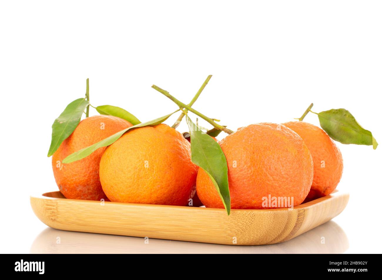 Diversi tangerini maturi di arancio brillante su un piatto di bambù, primo piano, isolato su bianco. Foto Stock